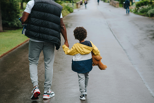 Adult and child walking in street.