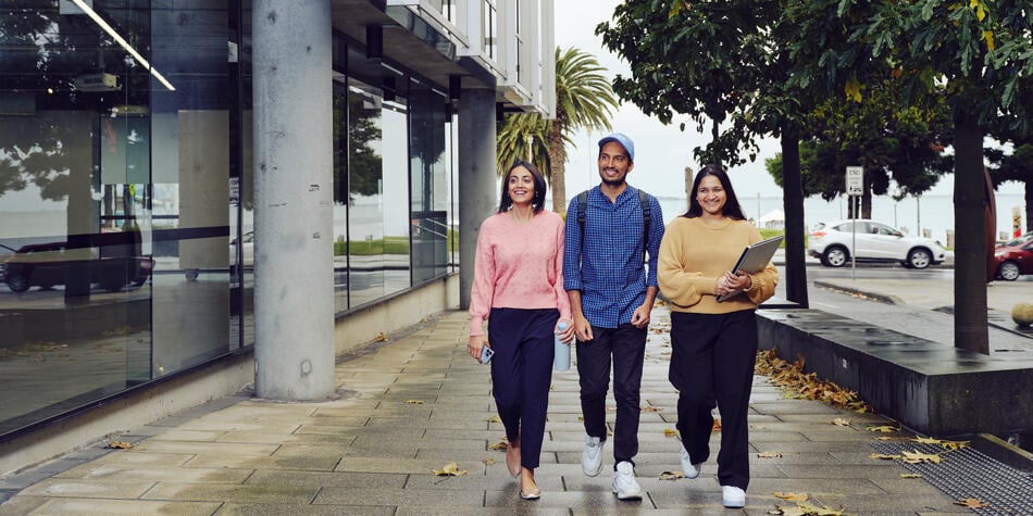Three students walking around the outside of the Geelong Waterfront Campus
