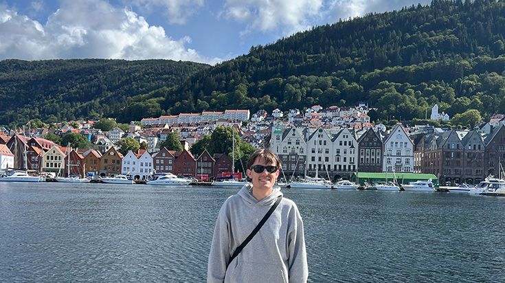 Student Zachary in front of the water, houses and mountains in Norway