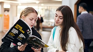 Two students discuss course options while looking at a course guide