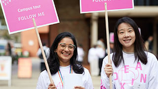 Two student campus tour guides holding signs